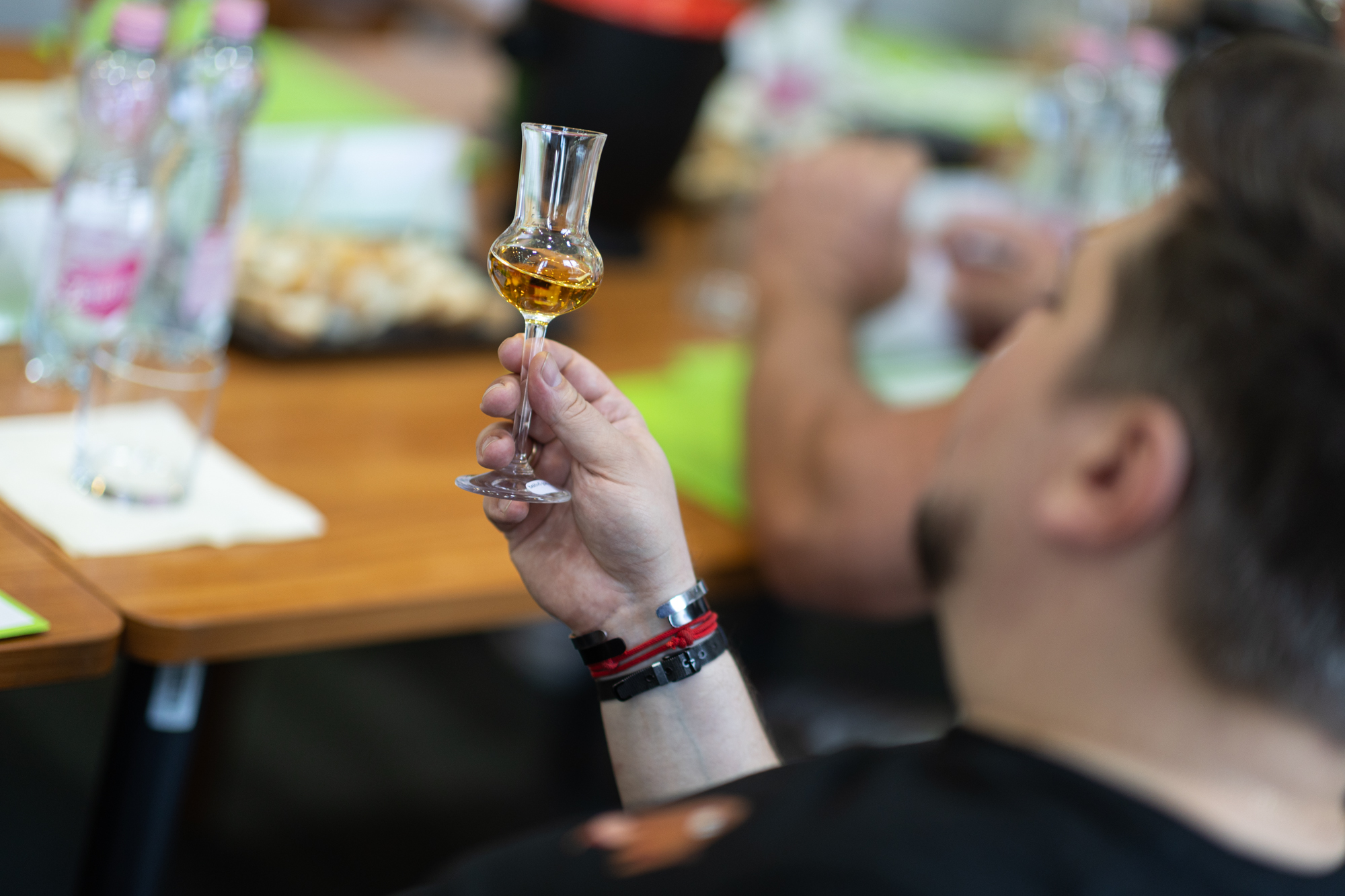 Egy férfi az asztalnál ülve poharat tarta a kezében, melyben rum van.