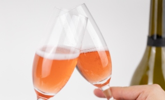 Koccintás két rozé pezsgőt tartalmazó pezsgős pohárral.